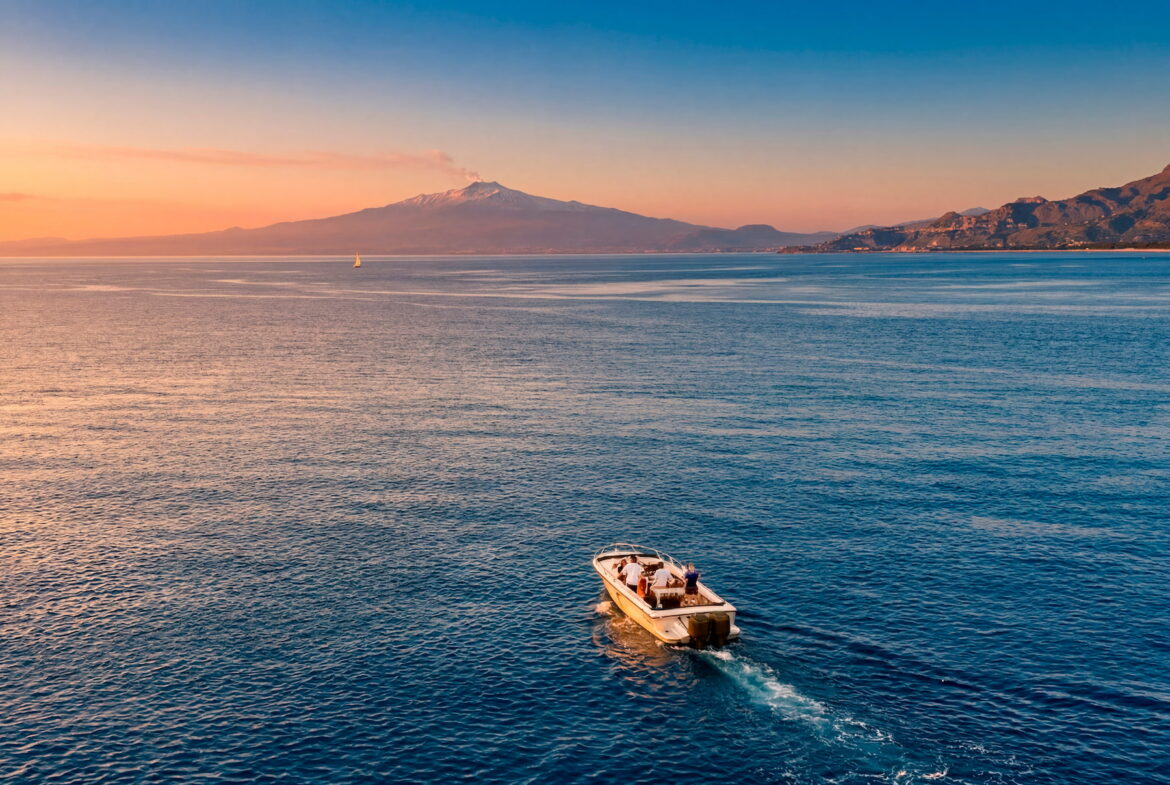 Private fishing boat cruising off the coast of Sicily with Mount Etna in the background